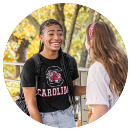Two students are facing each other talking and laughing