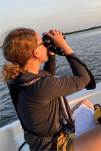 Kaitlyn Dirr on a boat while using binoculars