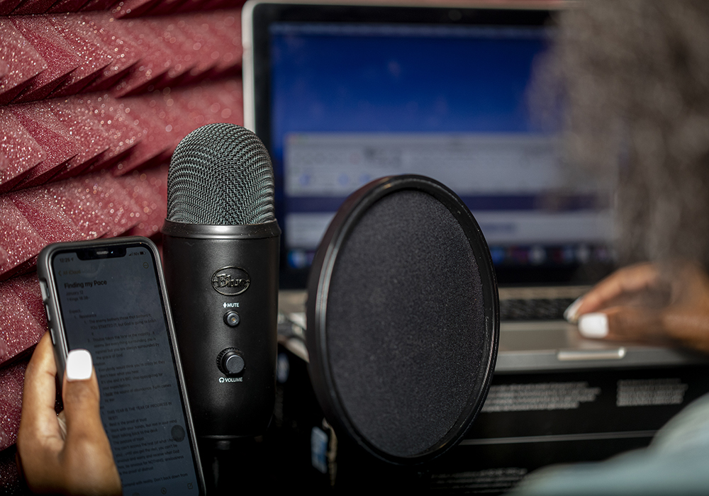 A person holds a phone next to audio recording equipment in a studio.