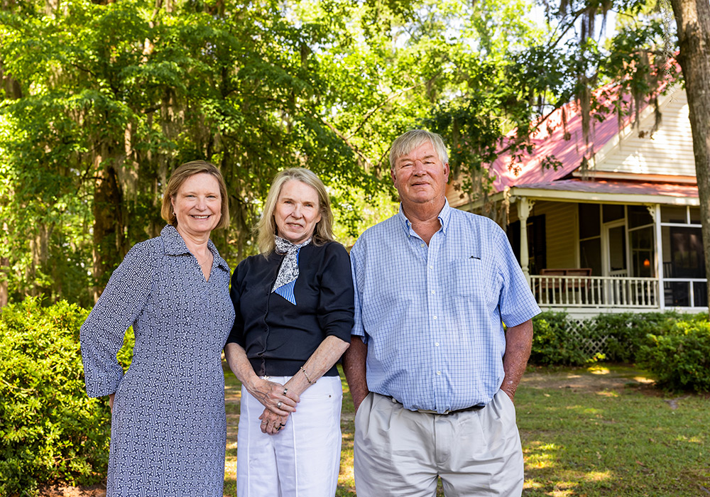 three people standing in front of a house