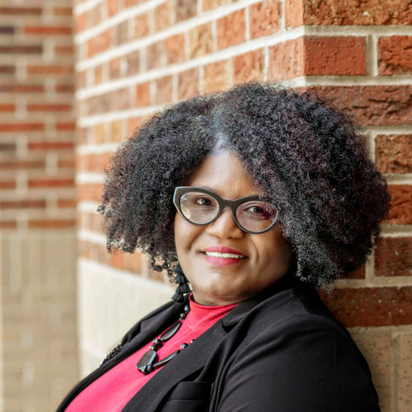 woman stands outside with a brick wall in the background